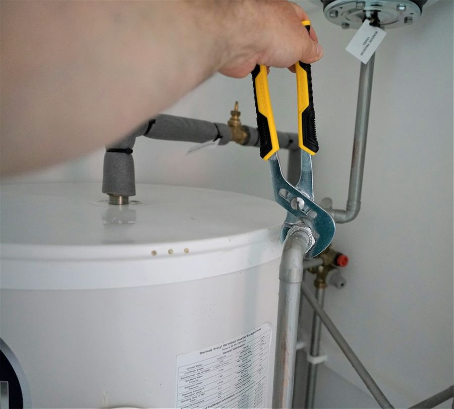 Engineer tightening a fitting on a hot water cylinder